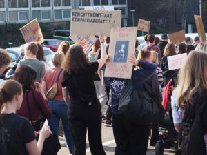 eine Personengruppe trägt verschiedene Pappschilder mit feministischen Parolen