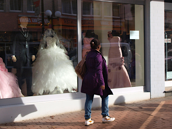 Eine Frau geht vor dem Schaufenster eines Ladens mit Hochzeitsmoden entlang.